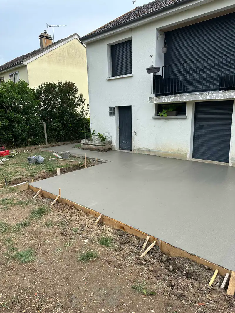 Dalle de terrasse en béton fraîchement coulée devant une maison