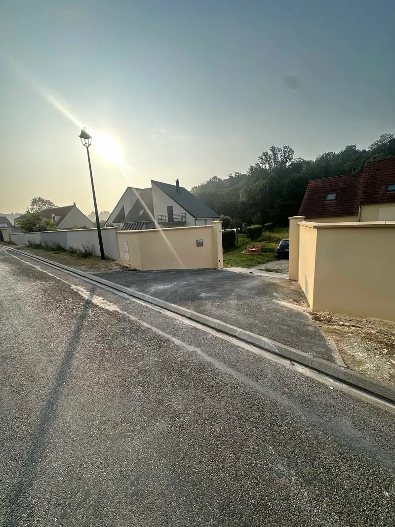 Mur de clôture enduit avec chaperon le long d'une rue