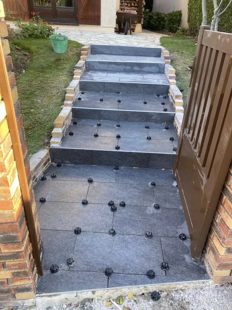 Pose de carrelage sur un escalier extérieur avec cales de nivellement