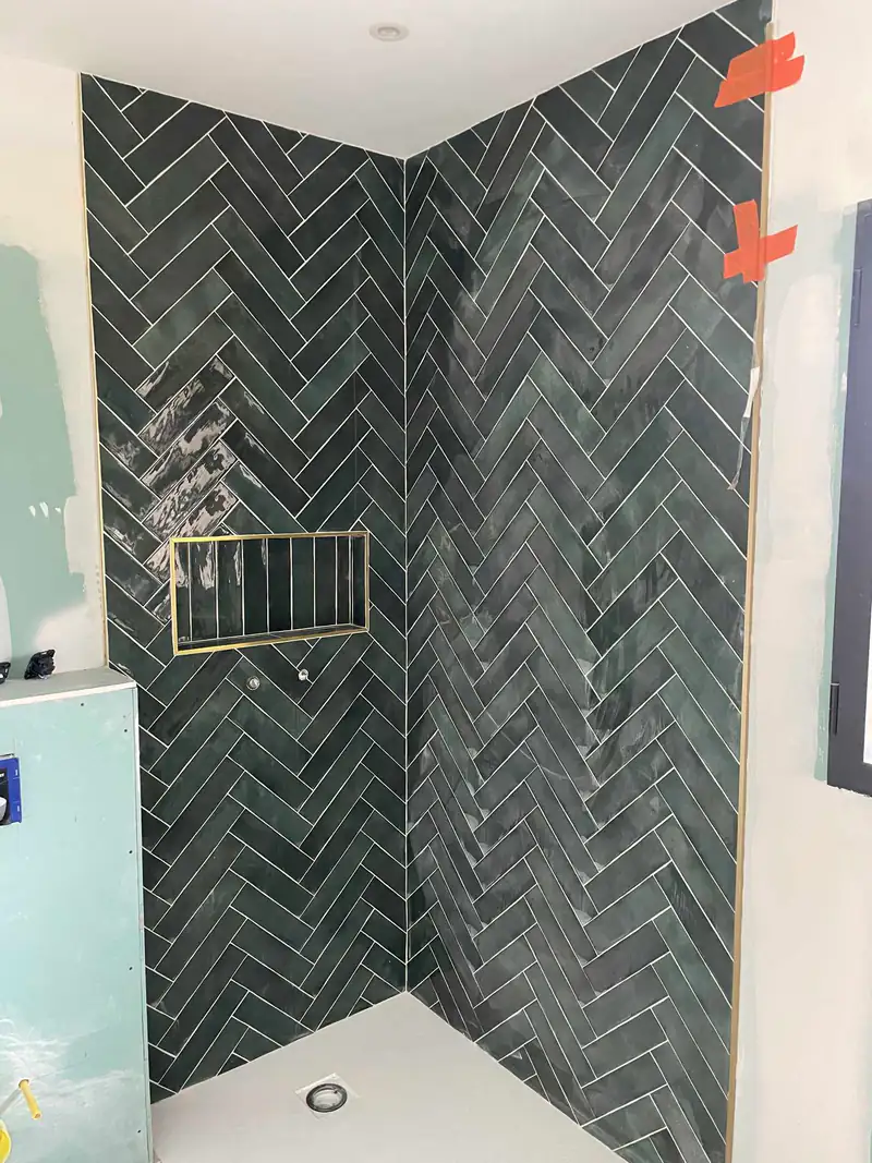 Faïence verte posée en chevrons avec niche de douche
