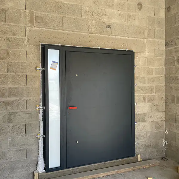 Porte d'entrée aluminium posée dans un mur en blocs béton