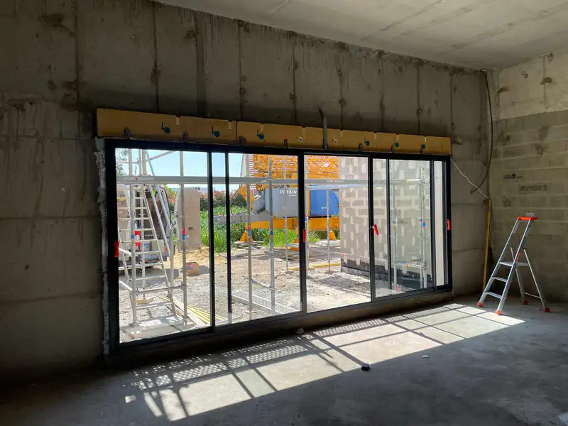 Baie vitrée coulissante posée dans une pièce en travaux